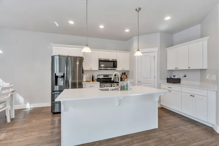 Kitchen with stainless steel appliances, white cabinets, and pendant lighting
