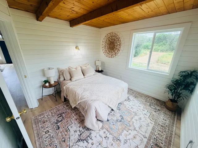 Shiplap paneled walls complement the exposed wood beam ceiling in this bright room