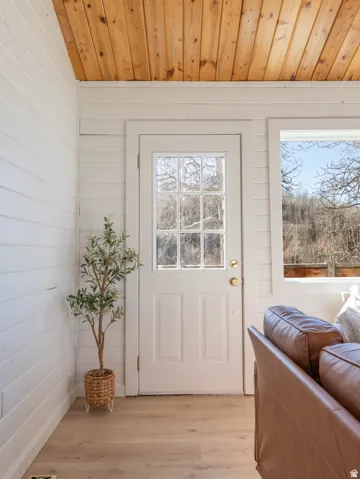 Doorway to west deck with wood ceiling, wood finished floors, and wood walls