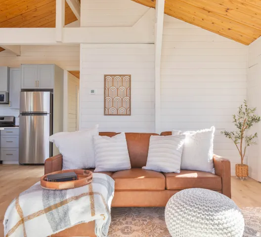 Living area with light wood-style flooring, a vaulted wooden ceiling, and wooden walls