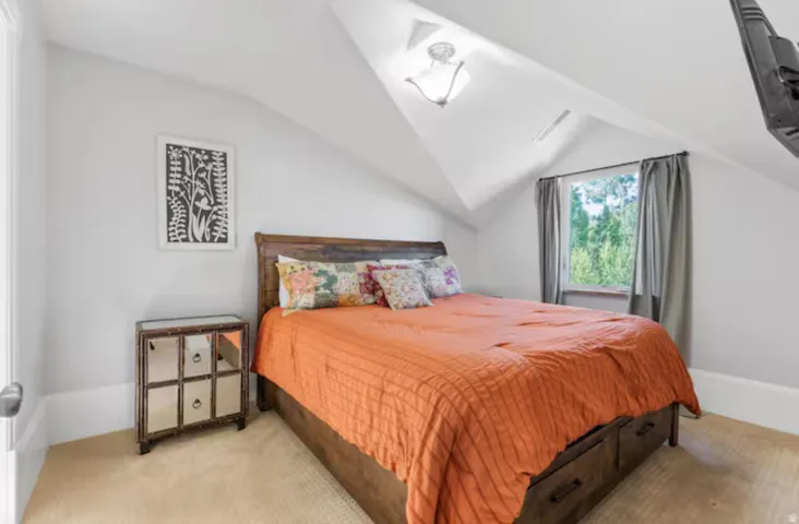 Bedroom featuring light carpet and lofted ceiling