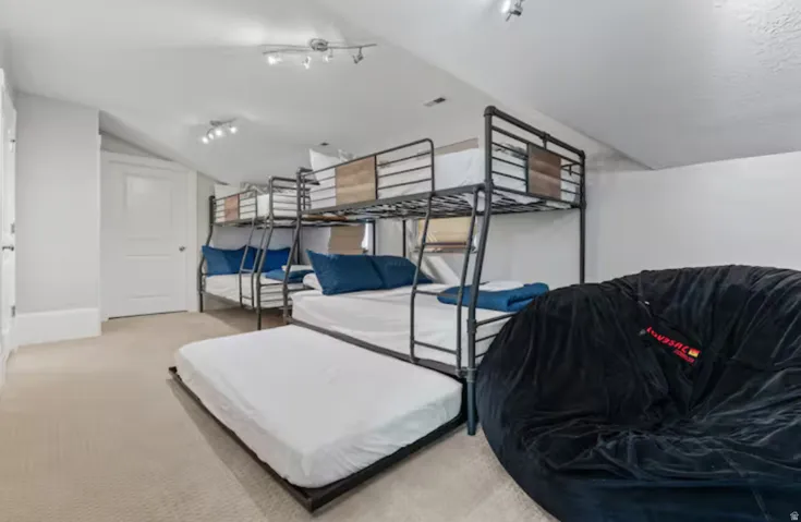 Bedroom featuring vaulted ceiling, carpet flooring, and rail lighting