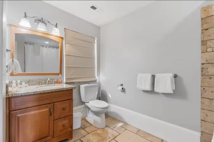 Full bath featuring vanity, stone tile flooring, and curtained shower