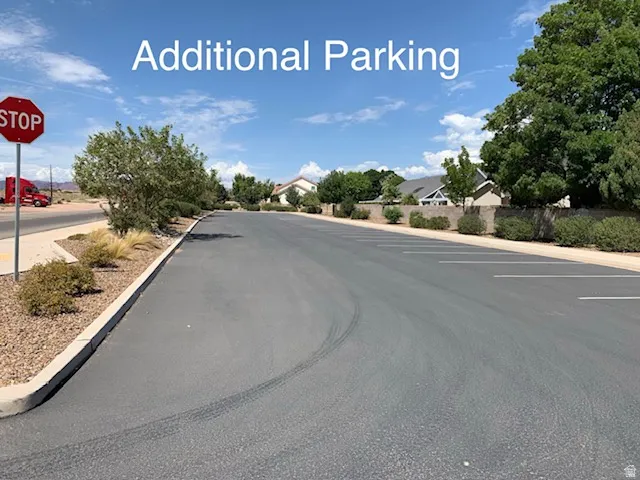 View of asphalt road featuring sidewalks, traffic signs, and curbs