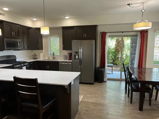 Kitchen featuring hanging light fixtures, stainless steel appliances, a kitchen breakfast bar, and dark wood finish cabinets