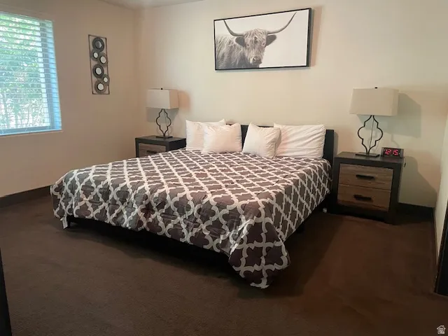 Bedroom with baseboards and dark colored carpet