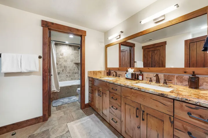 Full bath featuring stone tile flooring, double vanity, tiled shower / bath, and recessed lighting