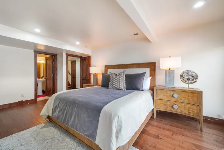 Bedroom featuring hardwood / wood-style floors, recessed lighting, beamed ceiling, and ensuite bath