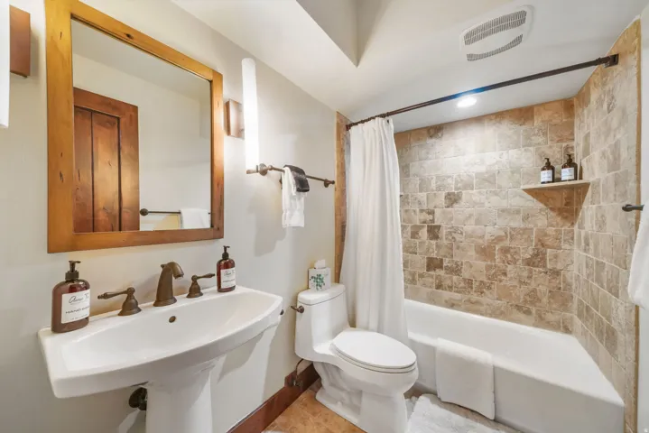Full bathroom with toilet and shower / bath combination with curtain