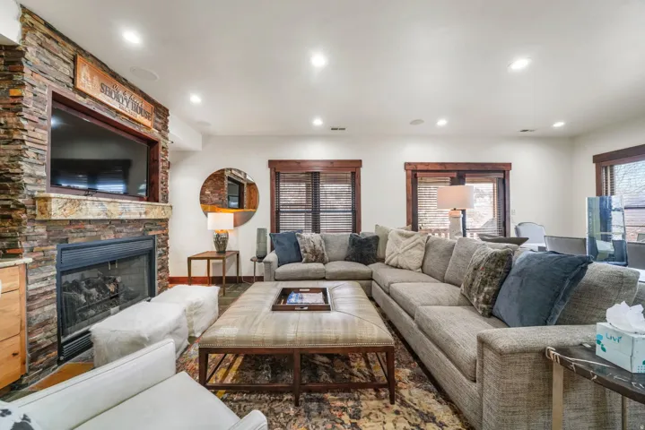 Living room with a stone fireplace and recessed lighting