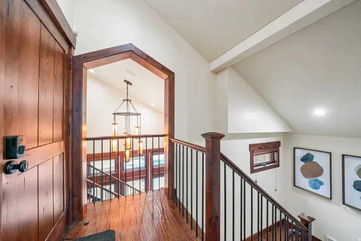 Hallway featuring lofted ceiling with beams, hardwood / wood-style floors, an upstairs landing, and suspended lighting