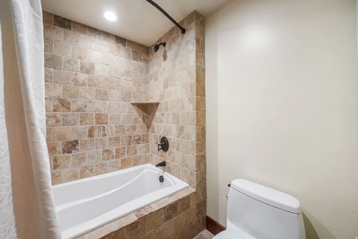 Full bathroom with tiled shower / bath combo and recessed lighting