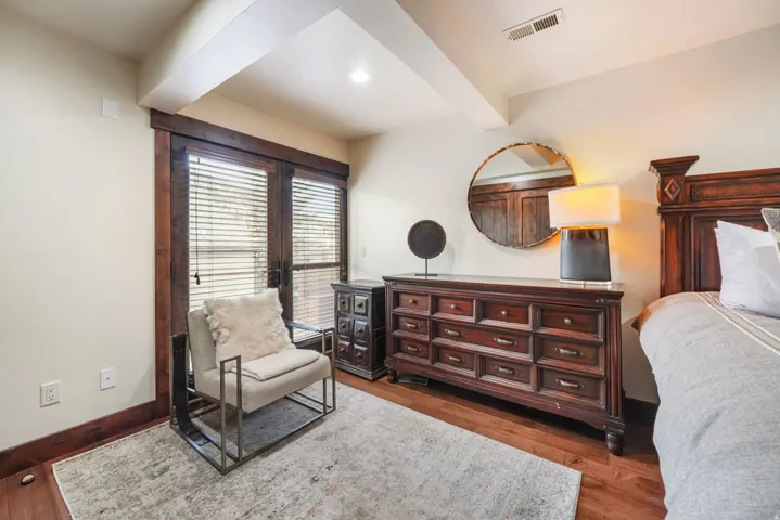 Bedroom with beamed ceiling, dark wood-style flooring, and french doors