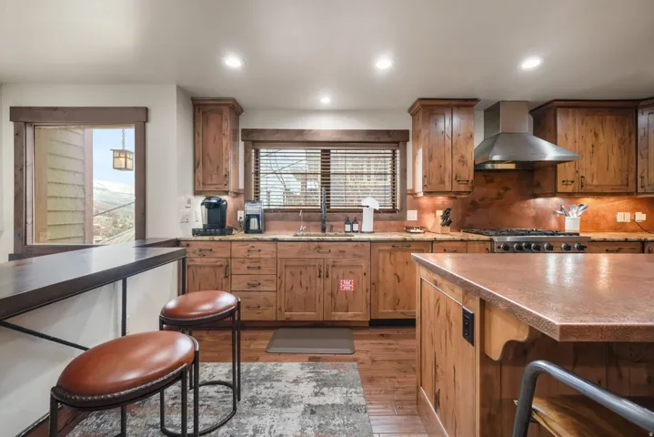 Kitchen with a kitchen breakfast bar, light wood finished floors, backsplash, wood finish cabinets, and plenty of natural light