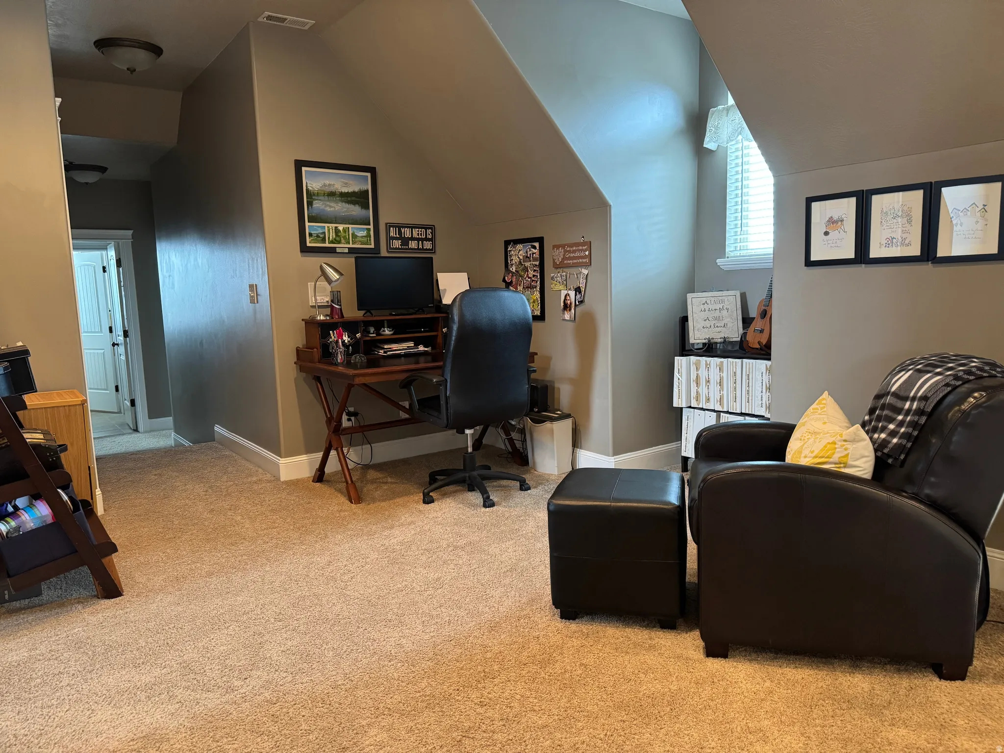 Office space featuring light colored carpet and vaulted ceiling