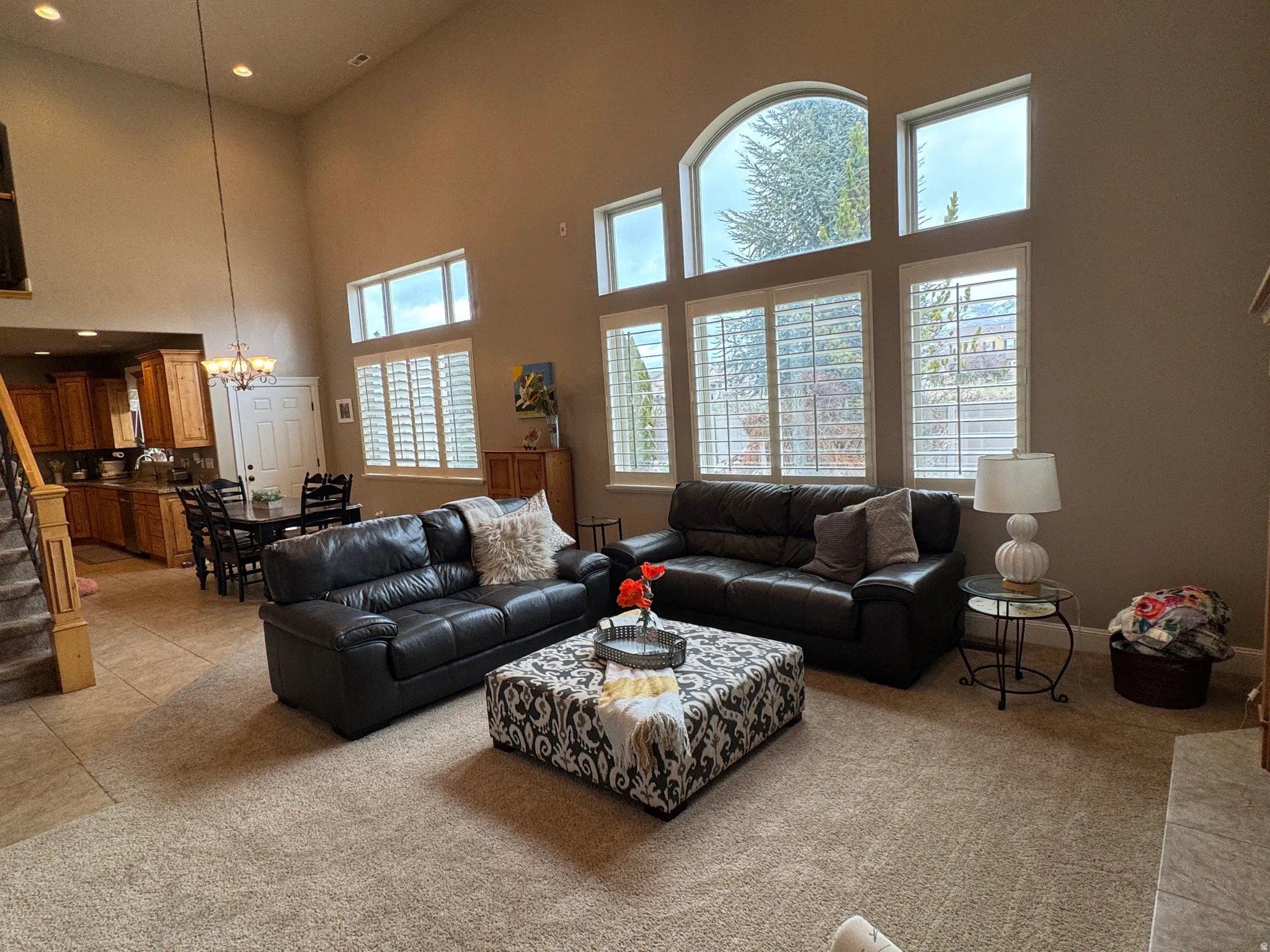 Living room featuring light carpet, a chandelier, and a high ceiling