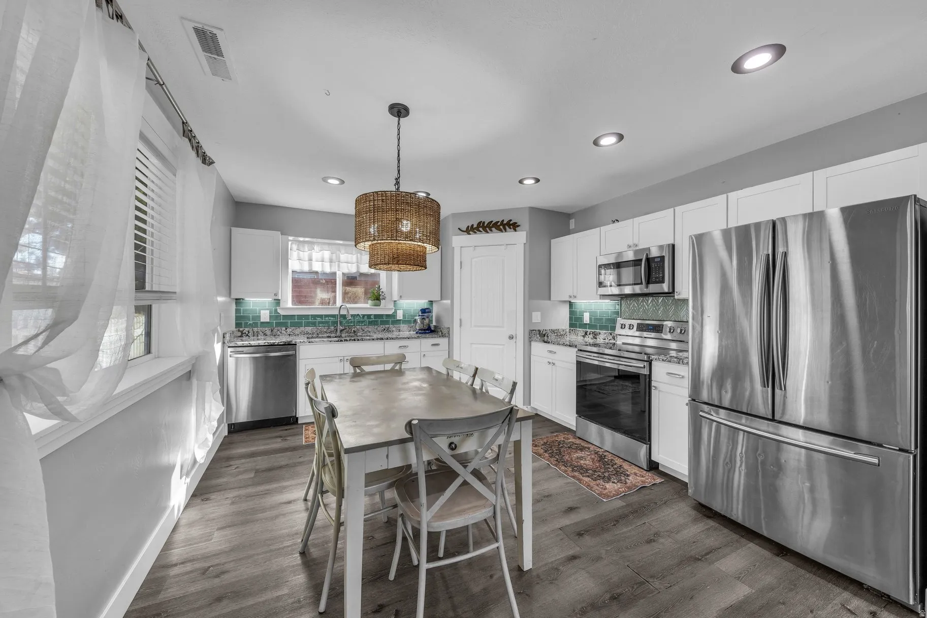 Kitchen with stainless steel appliances, white cabinets, and decorative backsplash