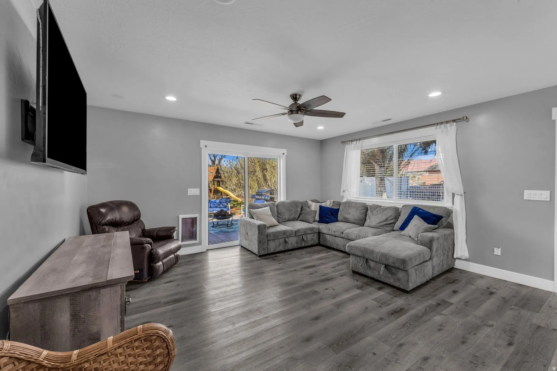 Living area with wood finished floors, a ceiling fan, healthy amount of natural light, and recessed lighting