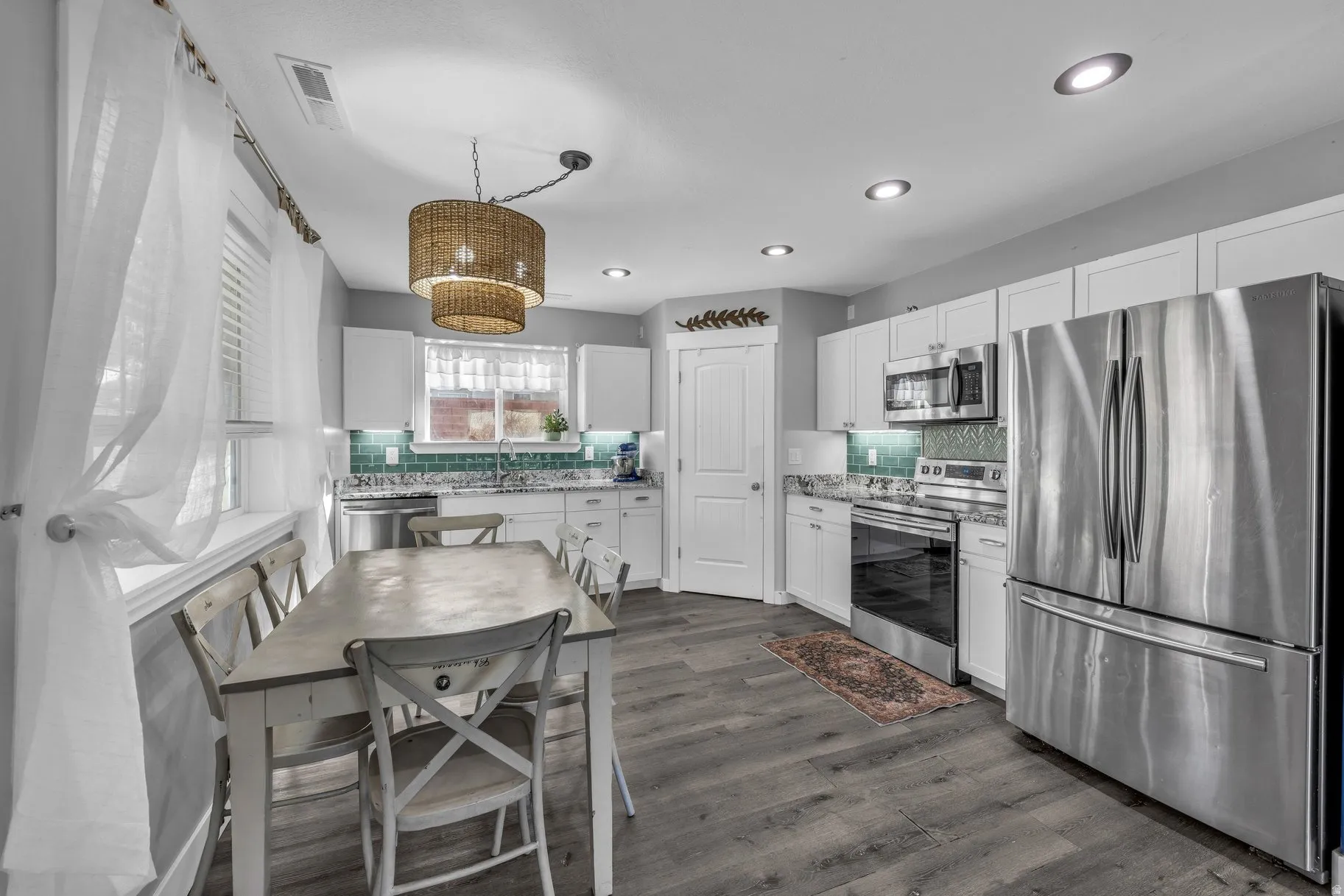 Kitchen with stainless steel appliances, white cabinets, backsplash, and dark wood-type flooring