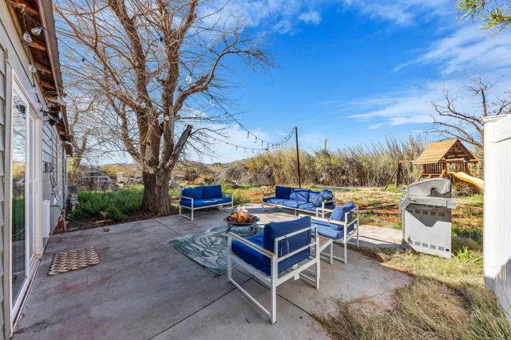 View of patio / terrace featuring an outdoor living space with a fire pit, a playground, and grilling area