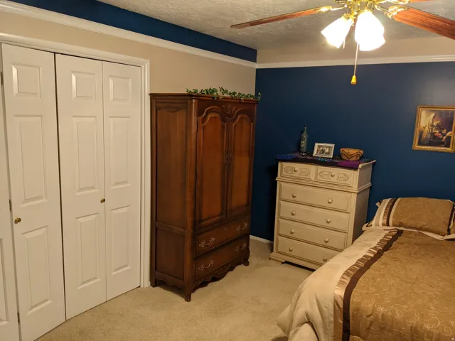 Bedroom with a closet, a textured ceiling, light carpet, and ceiling fan