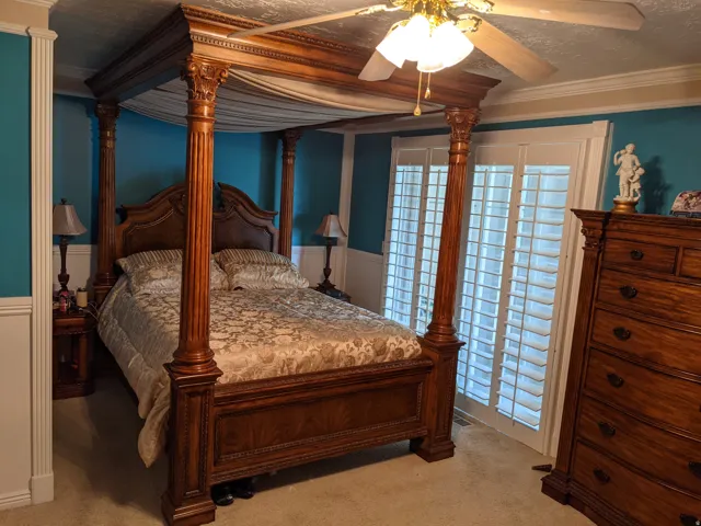 Bedroom featuring ornamental molding, ceiling fan, light colored carpet, and a wainscoted wall