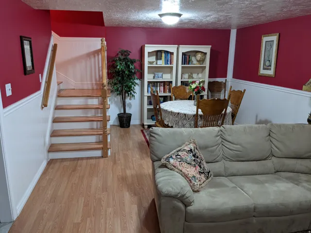 Living room with wainscoting, light wood-style floors, and a textured ceiling