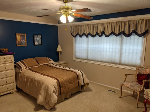 Bedroom featuring light colored carpet, ceiling fan, and a textured ceiling