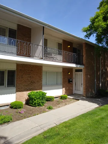 View of front of property with a balcony and brick siding