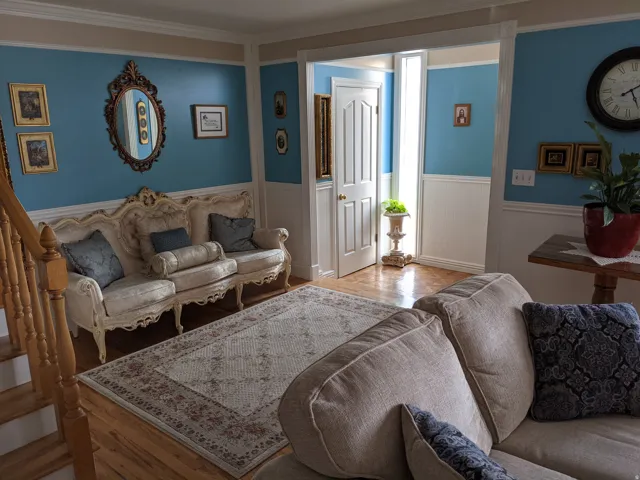 Living room with wood finished floors, wainscoting, and ornamental molding