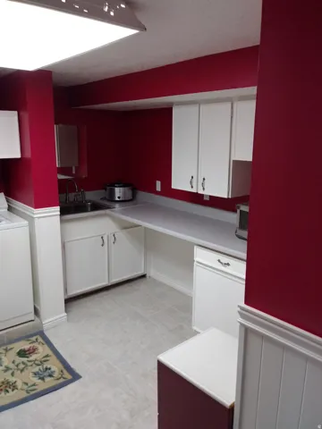 Kitchen with white cabinets, a wainscoted wall, washer / dryer, and light countertops