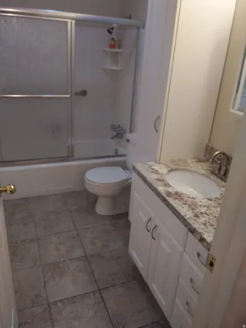 Full bathroom with vanity, enclosed tub / shower combo, and light tile patterned flooring