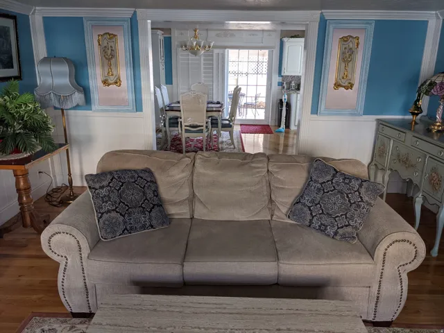 Living room featuring wood finished floors, suspended lighting, a wainscoted wall, ornamental molding, and a decorative wall