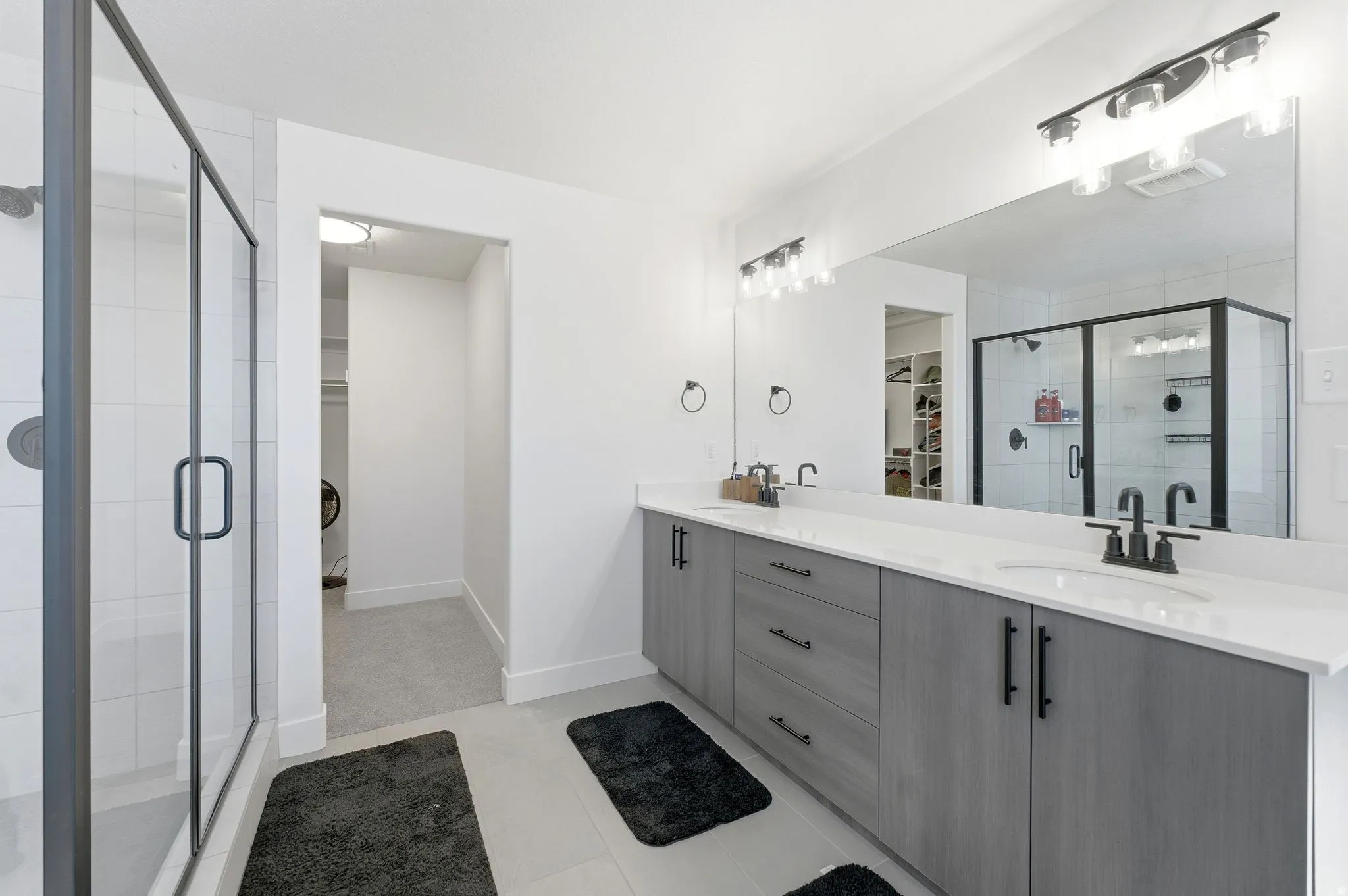 Bathroom with a spacious closet, a stall shower, double vanity, and light tile patterned floors