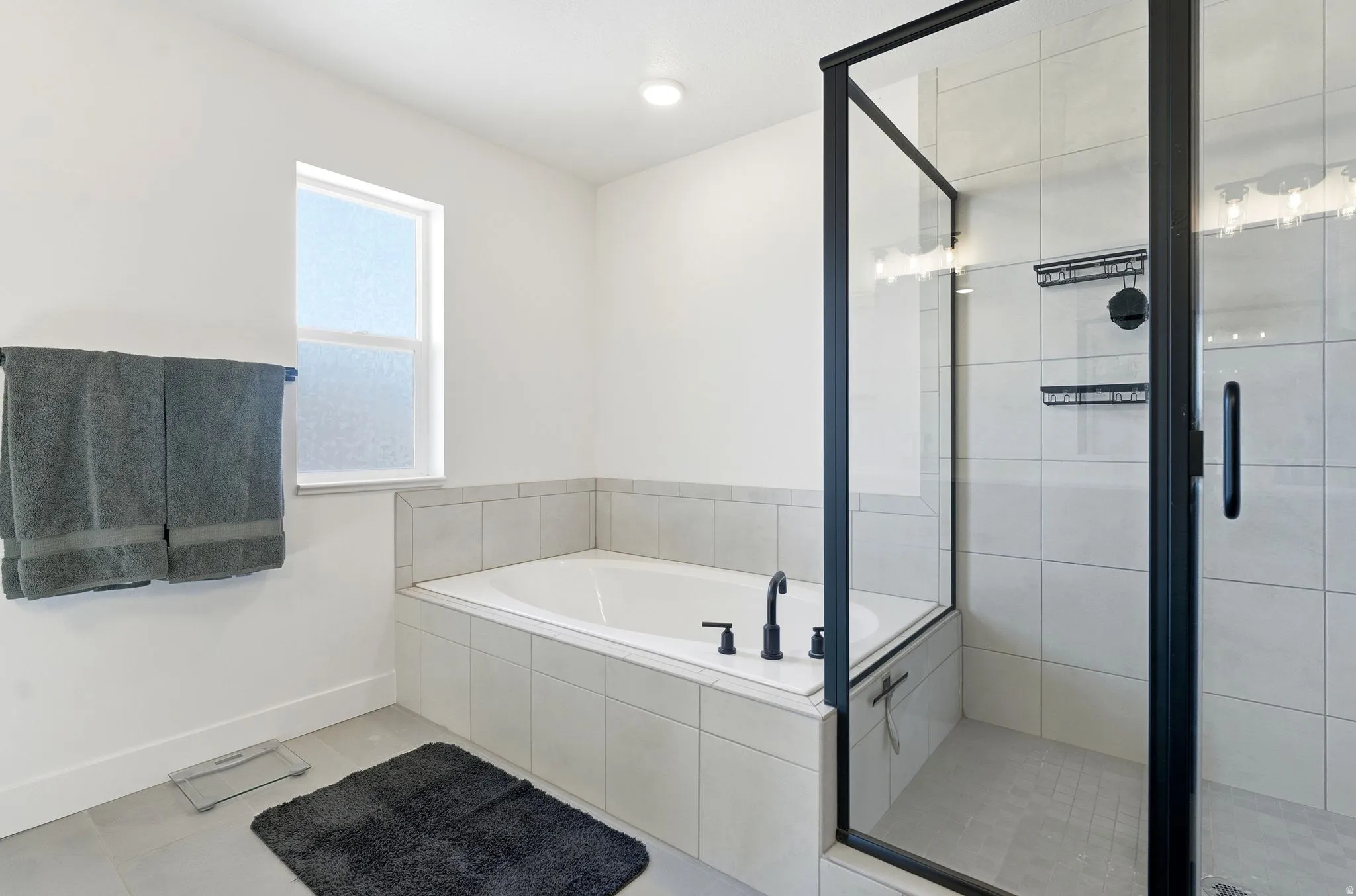 Bathroom with a shower stall, a bath, and light tile patterned floors