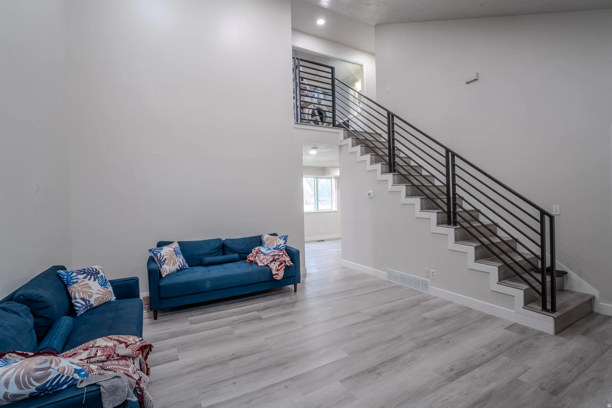 Living area featuring a high ceiling, light wood-style floors, and recessed lighting