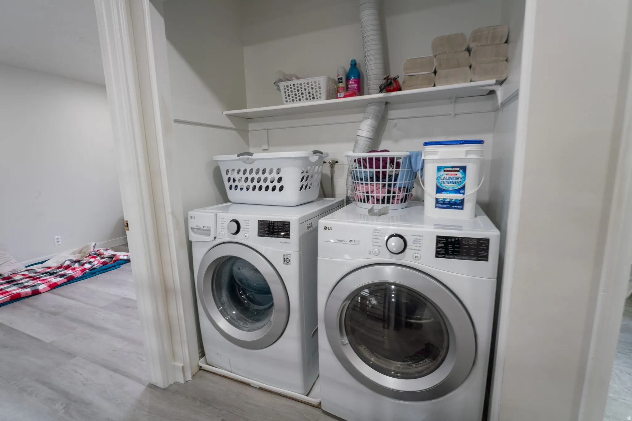 Laundry area with light wood finished floors and washer and clothes dryer