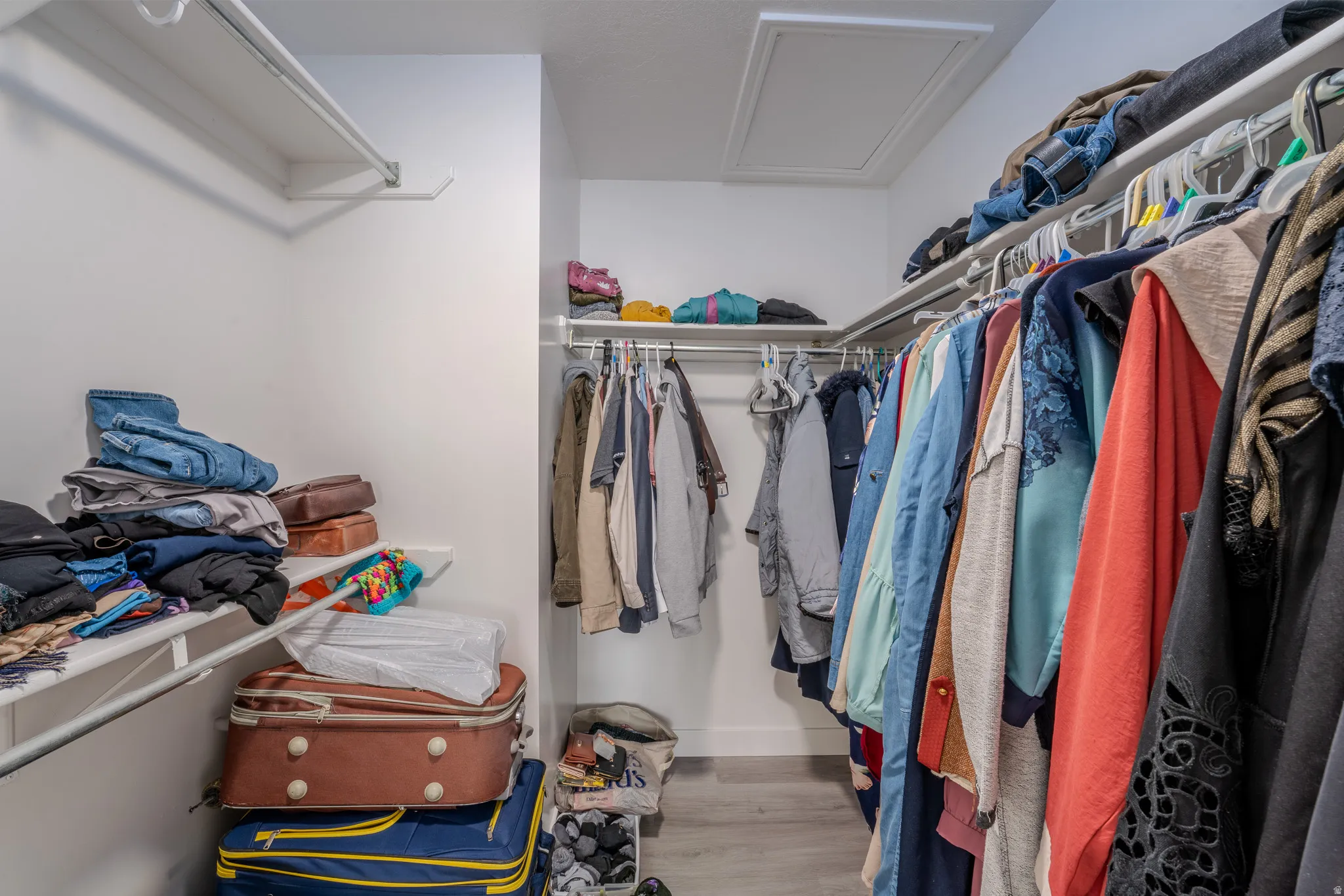 Walk in closet featuring attic access and light wood-style flooring