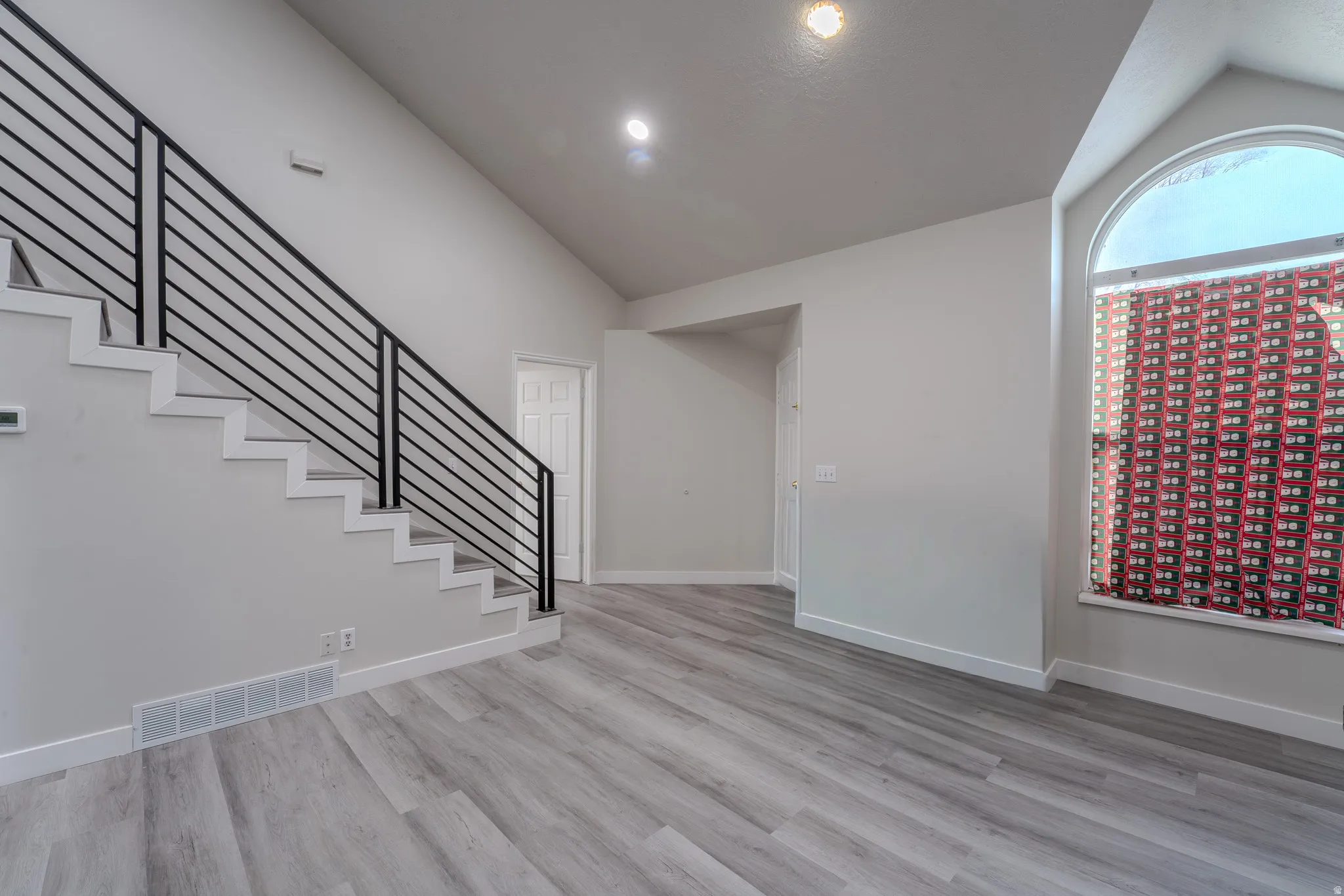 Unfurnished living room with lofted ceiling and light wood-style flooring