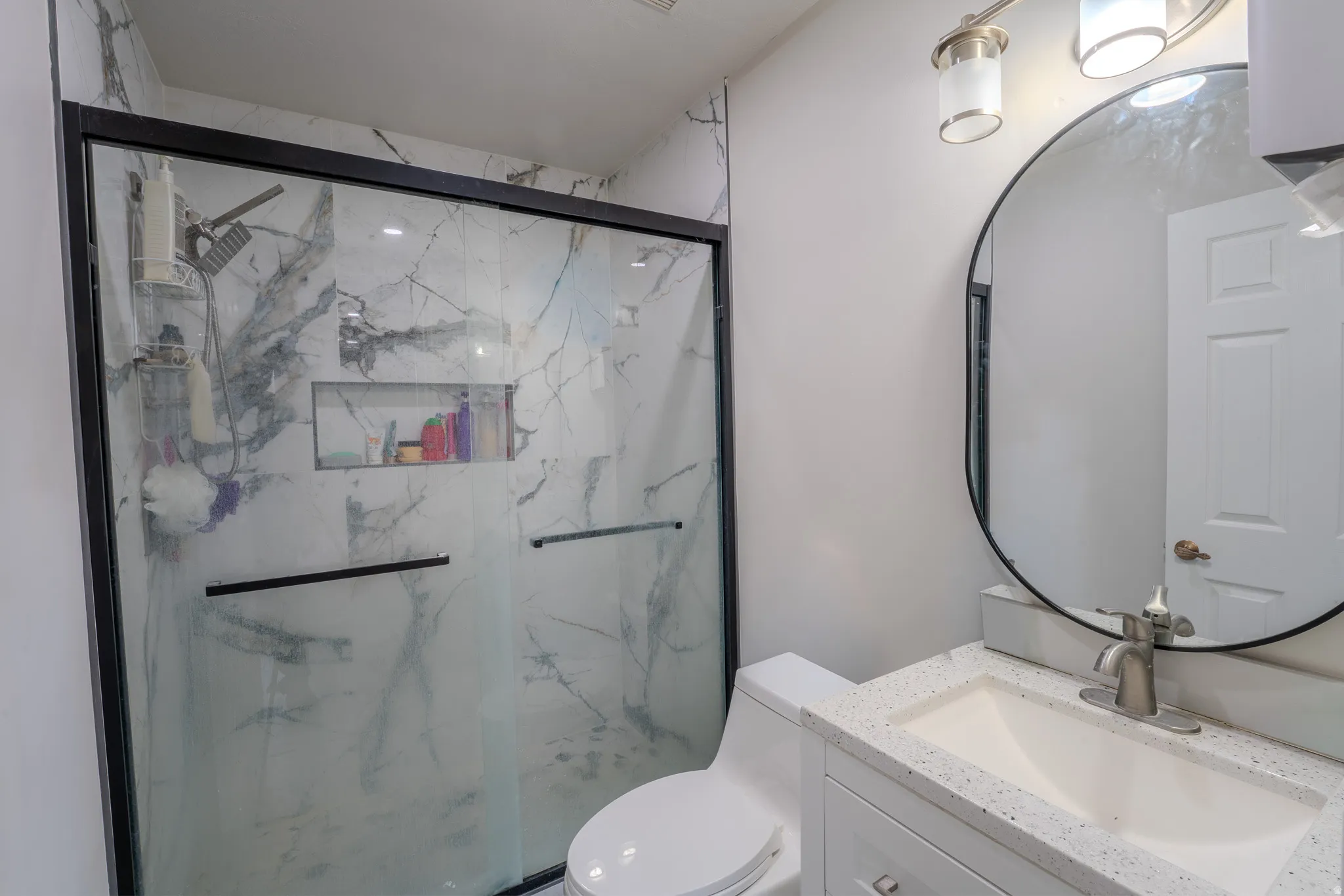 Bathroom featuring vanity and a marble finish shower