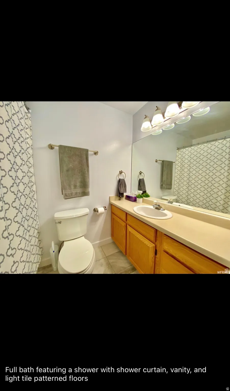 Full bathroom featuring vanity, a shower with shower curtain, and light tile patterned flooring