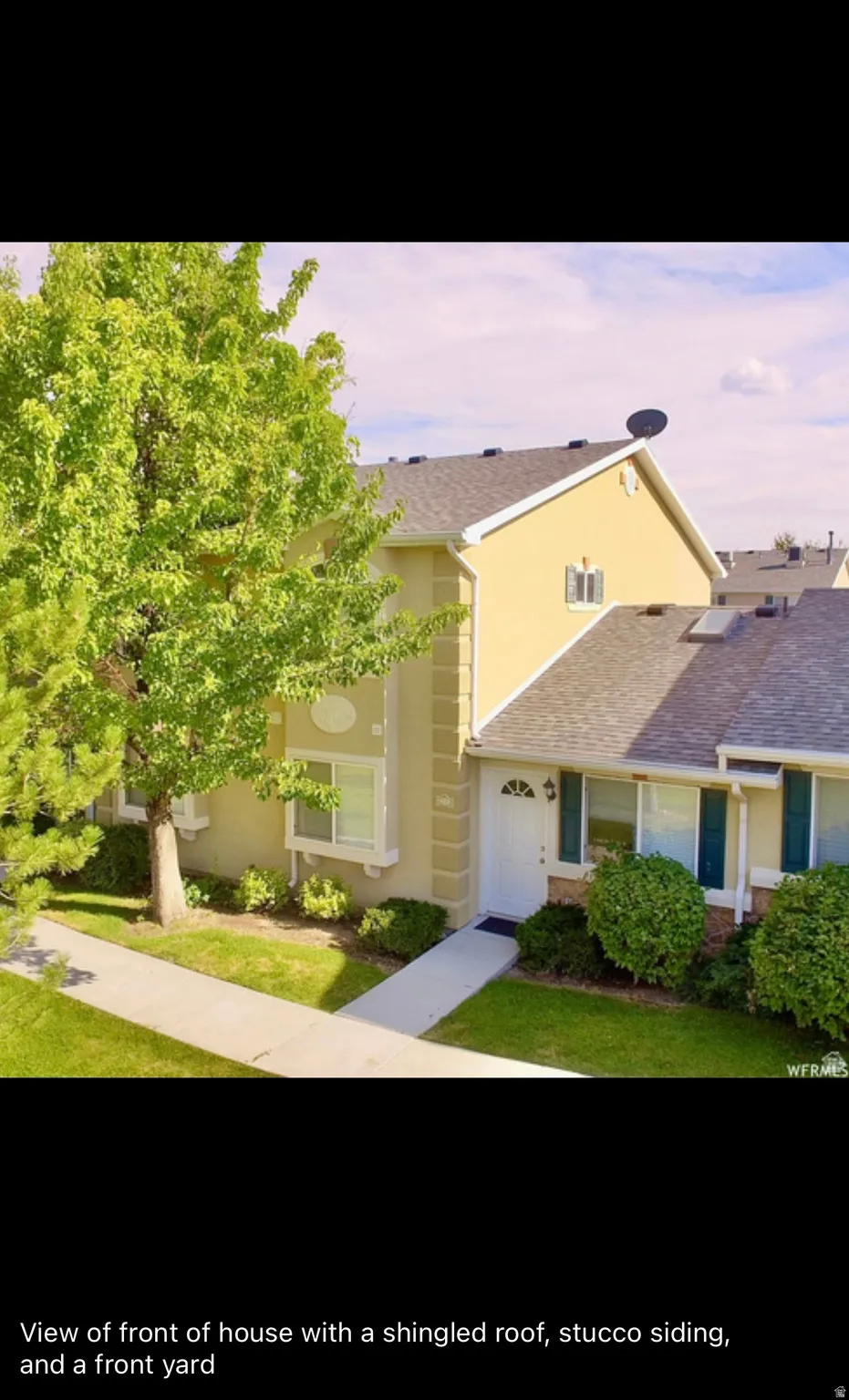 View of front of house featuring stucco siding, roof with shingles, and a front yard