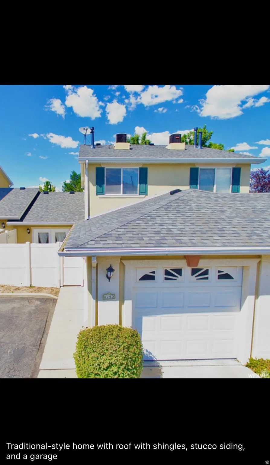 Traditional-style house featuring a garage, a shingled roof, stucco siding, and driveway