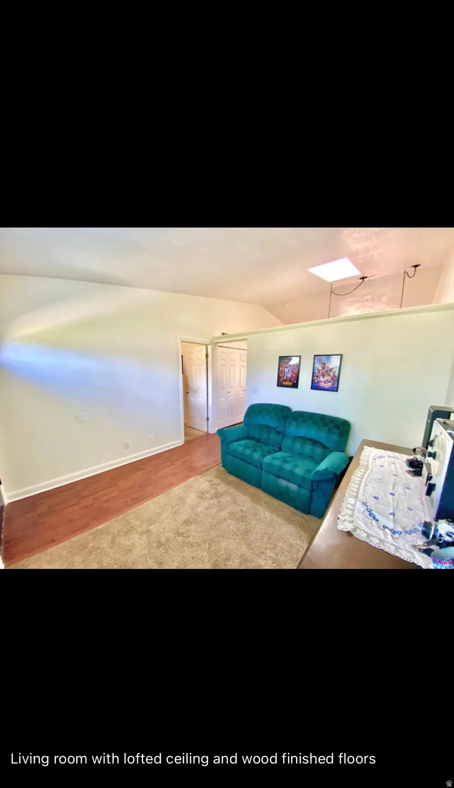 Living area featuring wood finished floors, lofted ceiling, and a skylight