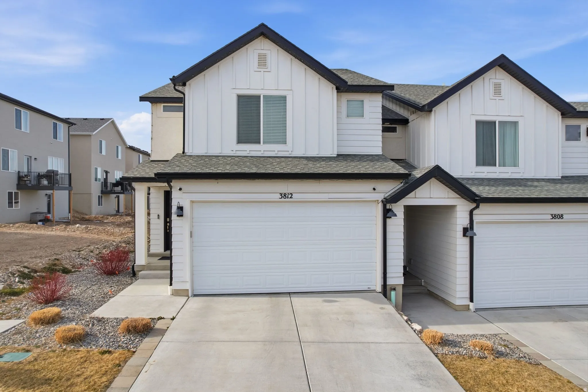View of front of house featuring board and batten siding, roof with shingles, concrete driveway, and an attached garage
