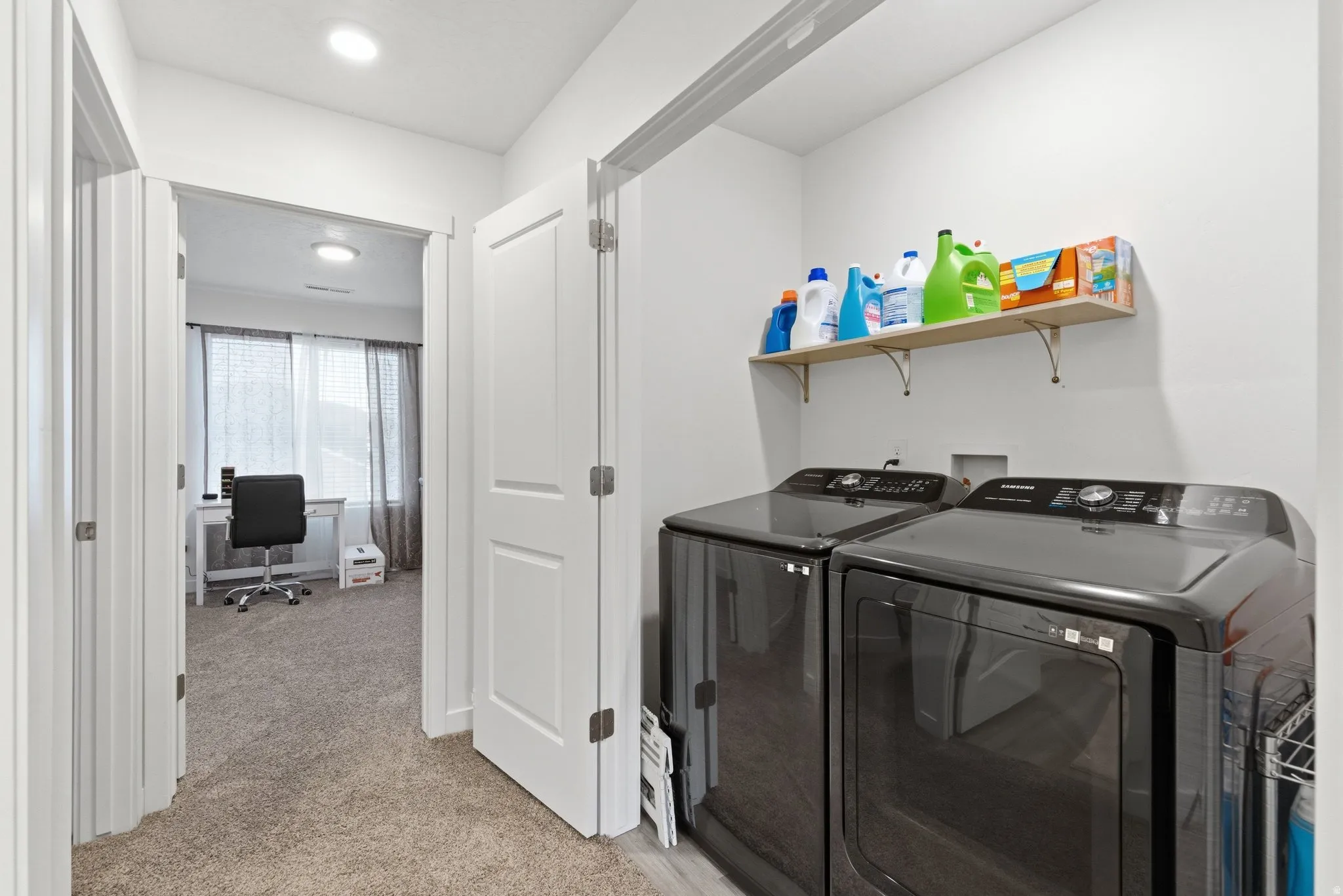 Laundry area with light colored carpet, an office area, and washer and dryer