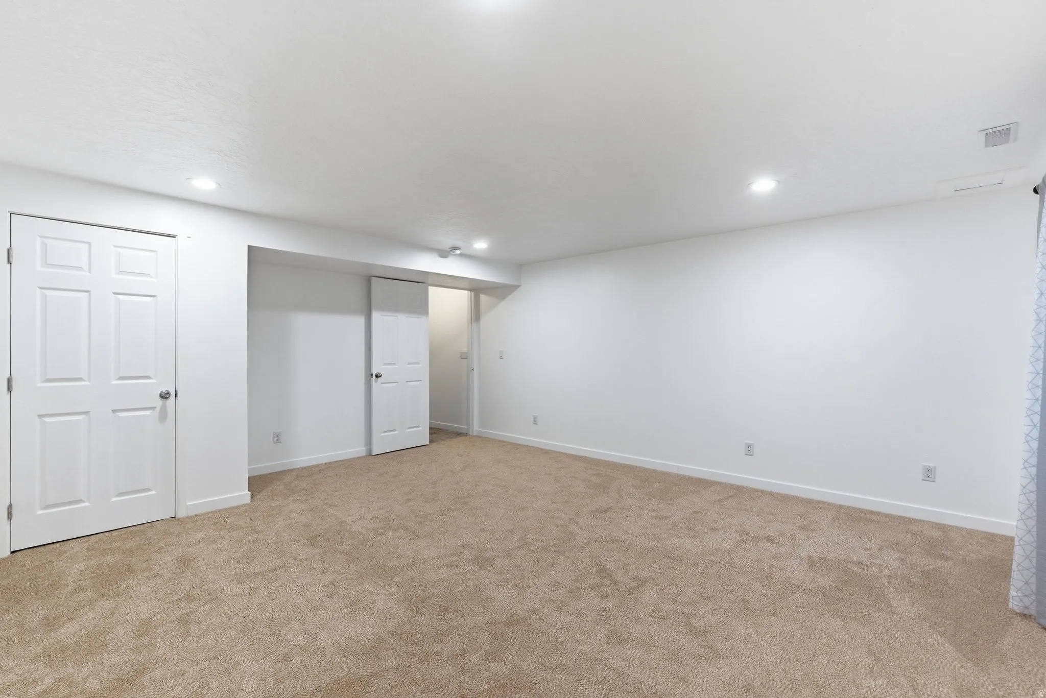 Finished below grade area with light colored carpet and recessed lighting