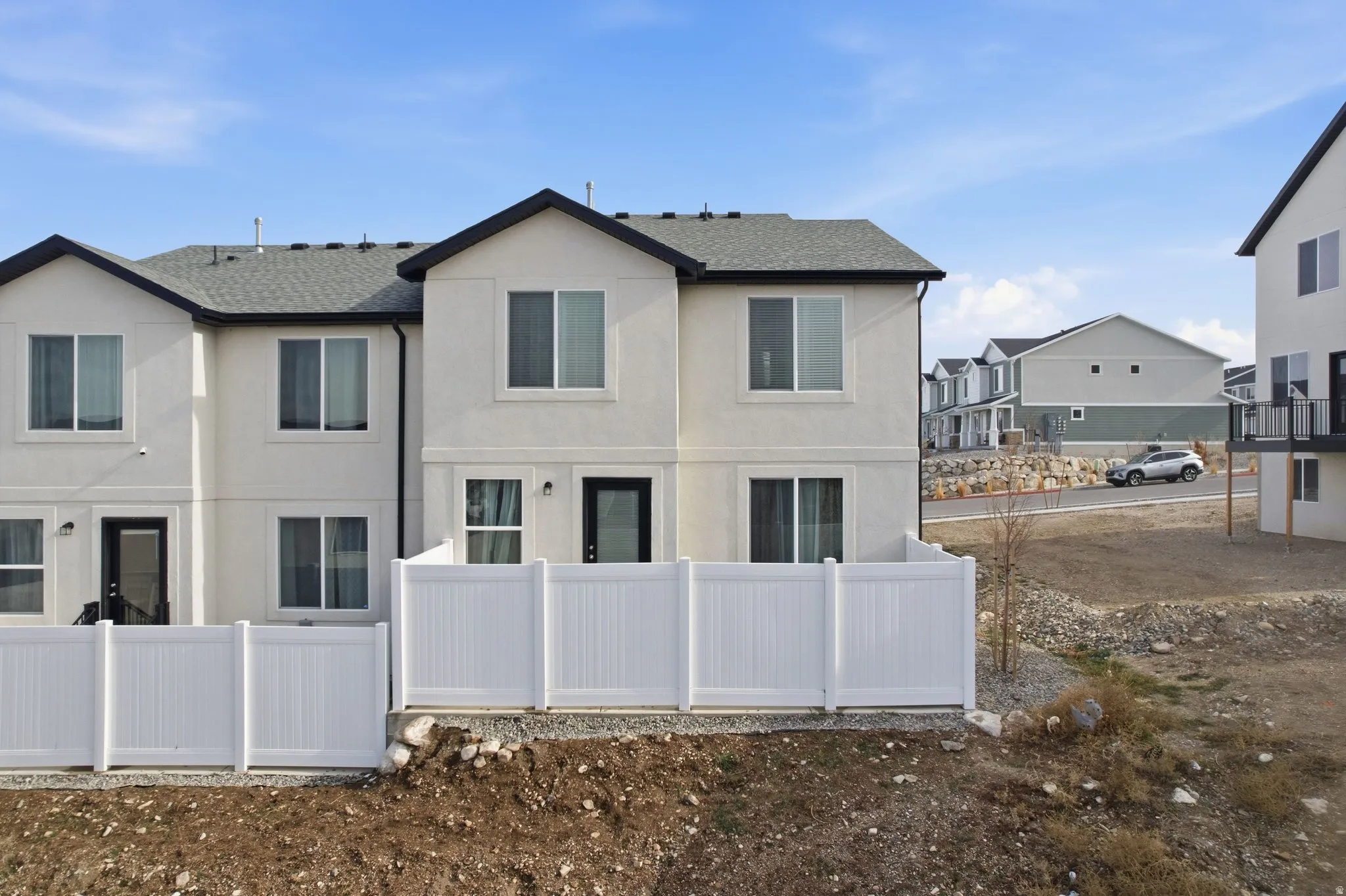 Rear view of house with stucco siding, a shingled roof, and a residential view