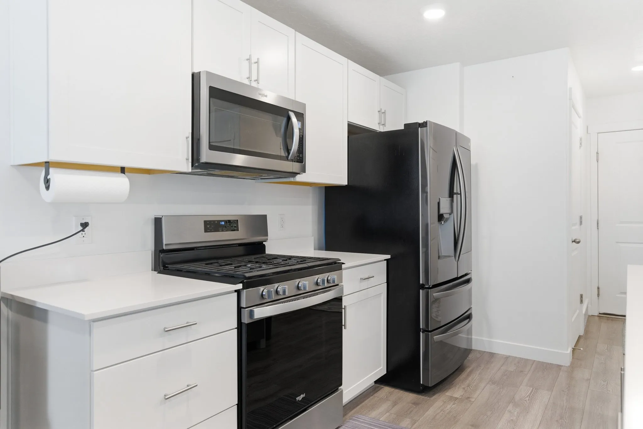 Kitchen featuring stainless steel appliances, white cabinets, light wood finished floors, and recessed lighting