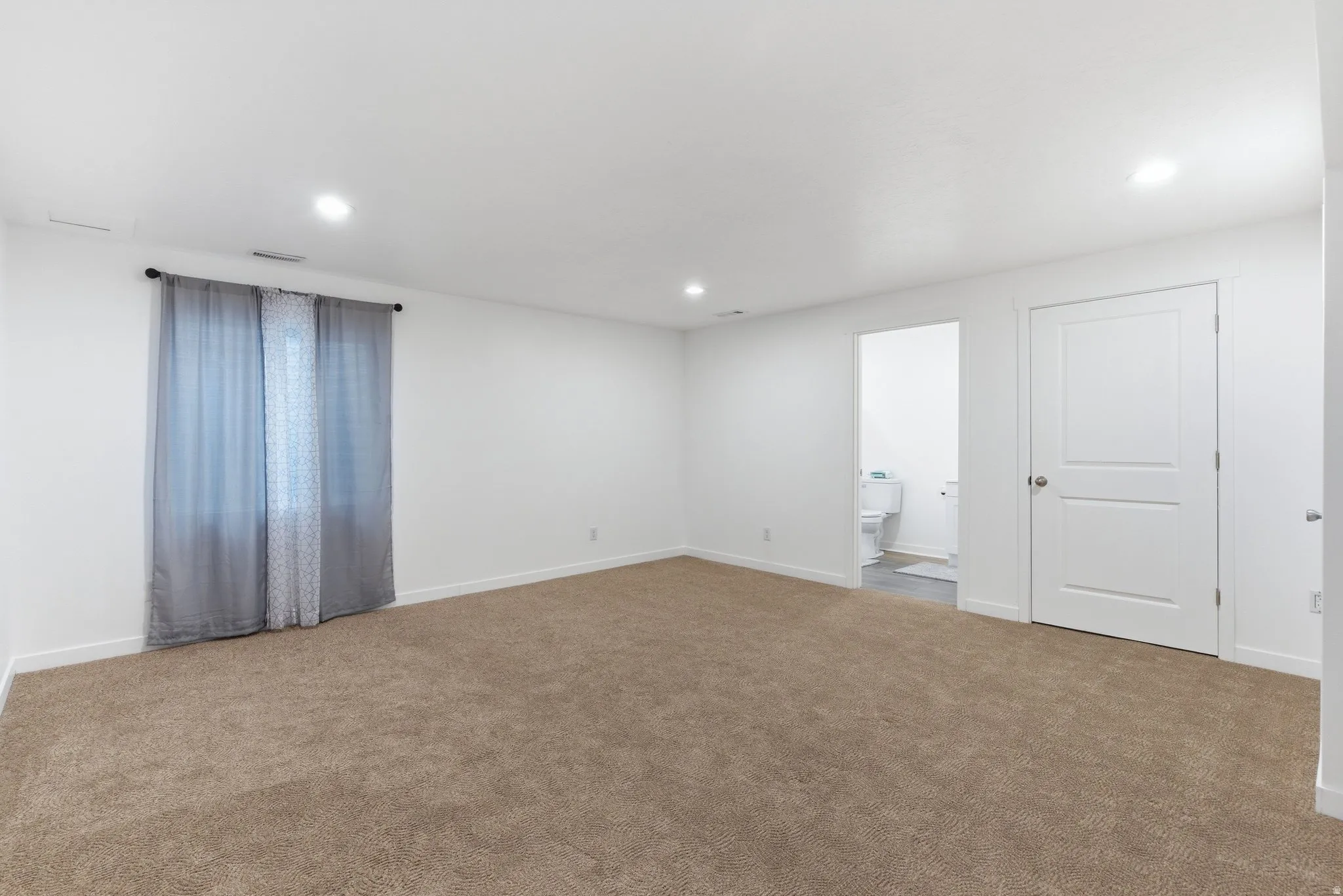 Carpeted empty room featuring baseboards and recessed lighting
